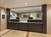 Hotel reception area with two dark wood front desks and computers, beige walls, tile flooring, and a painting on the wall.