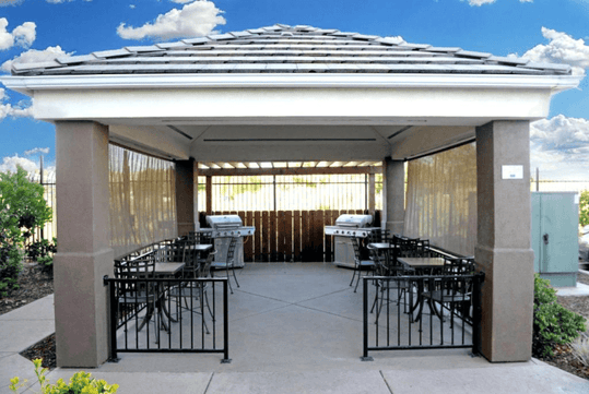 Outdoor gazebo with BBQ grills, chairs, and tables.
