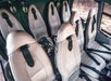 Eight gray leather seats in theatre style inside of a Maverick Airbus helicopter with rocks visible out of the far window.
