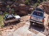 Two NAVTEC land cruisers navigating Elephant Hill in the Needles District of Canyonlands National Park on a sunny day.