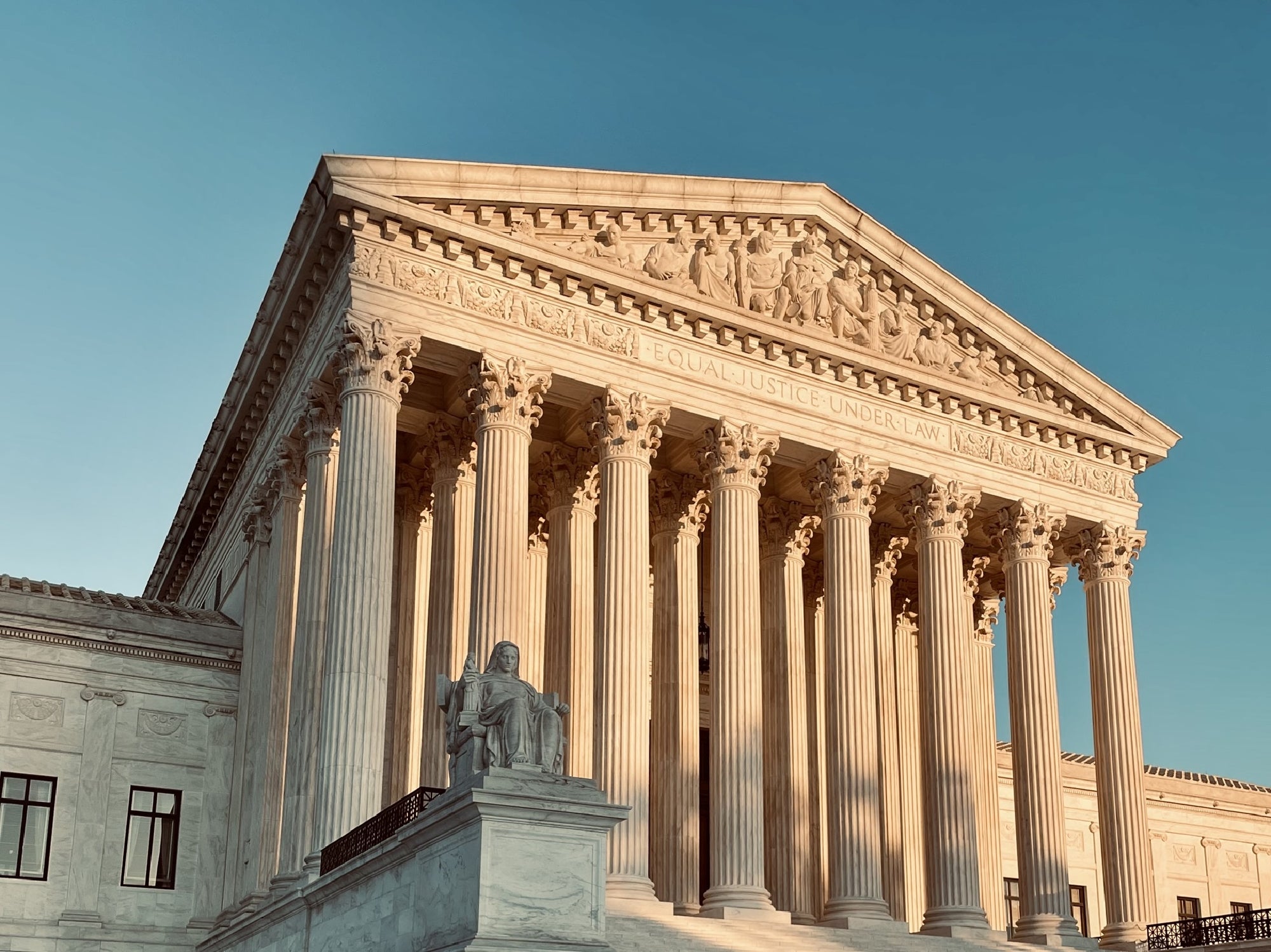 The United States Supreme Court building with classical columns and the inscription "EQUAL JUSTICE UNDER LAW" on the front facade, viewed in daylight.