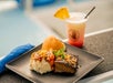A plate of delicious food, including a serving of beef, mashed potatoes with carrots, a roll, and a tropical drink, all presented in a vibrant setting.