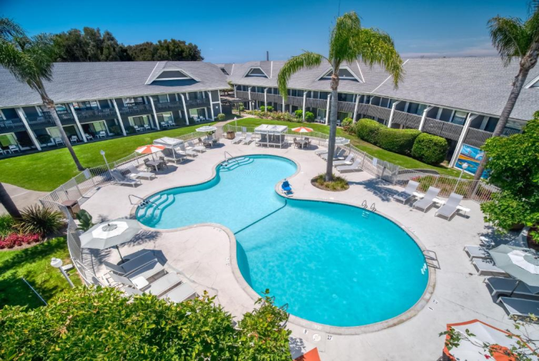 Outdoor pool, sun loungers with umbrella, and cabanas.