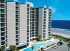 Tall buildings, an outdoor pool and a hot tub with the view of the ocean in the back.