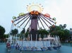 A large swing ride at Castle park, featuring colorful lights and several swings hanging from a central tower, set against a twilight sky.