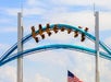 A blue two railed rollercoaster with guests in yellow seats going upside down on a sunny day at Cedar Point.