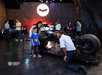 Visitors view and take photos with the Batpod motorcycle display at Warner Bros. Studio Tour Hollywood; several people are present in the exhibit area.