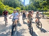 A group of people riding bicycles in a park on a sunny day.
