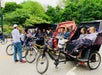 A large group listening to a guide during a Central Park pedicab tour.