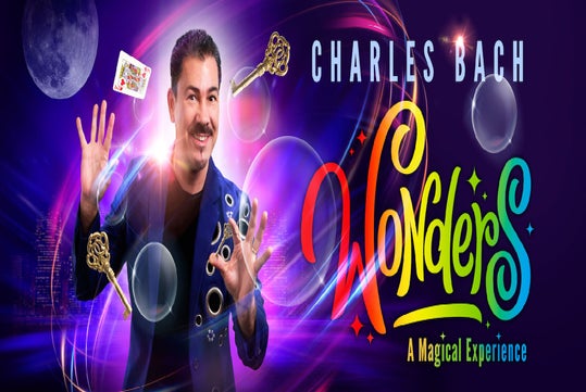 Magician Charles Bach performs with floating keys, bubbles, and a playing card, with colorful text reading “Wonders: A Magical Experience” against a vibrant cityscape background.