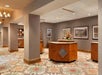 Hotel lobby with patterned carpet, wooden reception desks, and framed artwork on the walls.