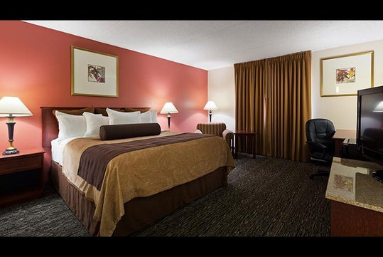 One king bed, a work desk and a flat-screen TV inside a guest room.
