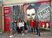 A tour group posed in front of a red and black mural where Dillinger took his last steps on the Chicago Crime Tours.