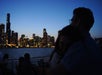 A couple viewing the illuminated city skyline from the water.