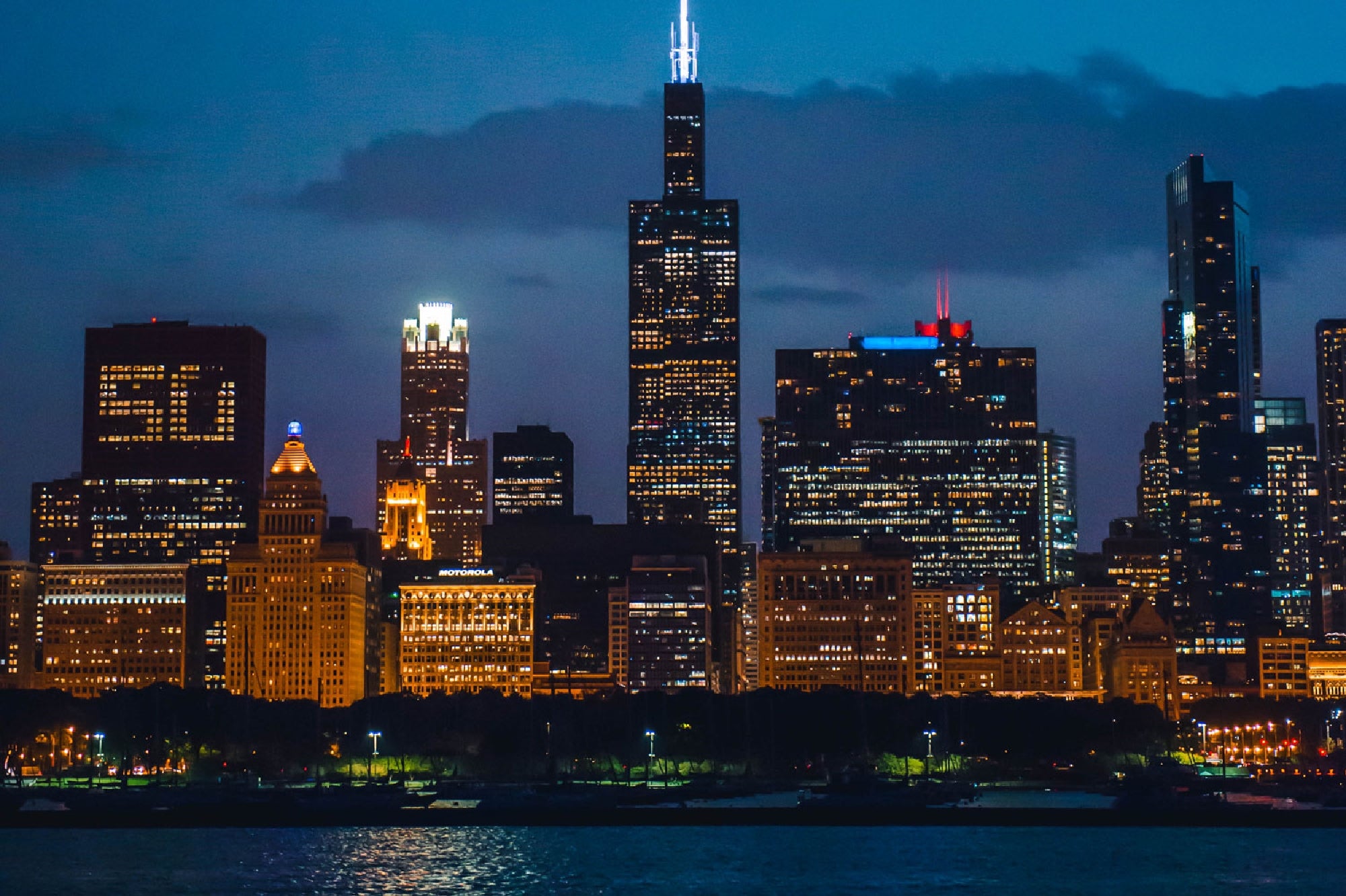 Illuminated skyscrapers overlooking the water in downtown Chicago.