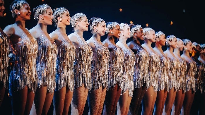 Close up of the Radio City Rockettes wearing shimmering silver costumes in a line on stage during the Christmas Spectacular.