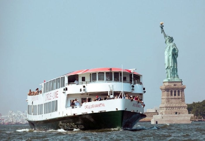 A Circle Line boat cruises past the Statue of Liberty on the Hudson River – admire Lady Liberty from the water