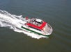 A red and white passenger ferry travels across the water with a group of people on board.