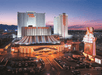 A brightly lit casino and hotel complex with large white towers, a circus-themed marquee, and a busy parking lot at dusk.