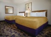 Two queen beds and bedside lamps in a guest room.
