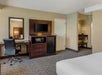 Hotel room with a desk, chair, TV, microwave, and mini-fridge. A bathroom is partially visible in the background.