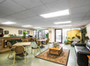 A brightly lit lobby with animal-print chairs, tables, a black sofa, potted plants, framed art, and a decorative folding screen with animal designs.