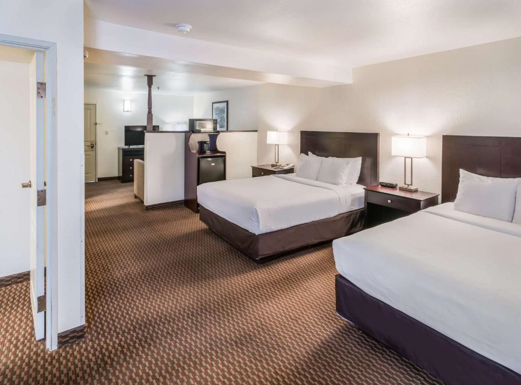 A well-appointed room with two queen beds, a mini-fridge, and a seating area, perfect for comfort and convenience.