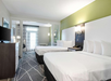The room features two queen beds and a TV, offering comfort and entertainment for a relaxing stay.