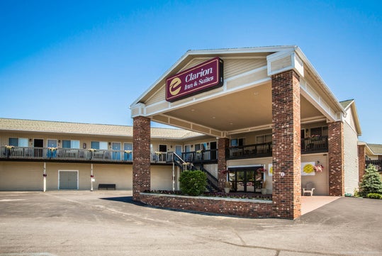 A two-story motel with a brick entrance, labeled "Clarion Inn & Suites," in a parking lot under a clear blue sky.