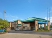 Hotel building with a green roof, three stories, and a covered entrance. A sign says "ENTER" and a white vehicle is parked nearby.