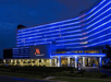 A modern hotel exterior at night with blue neon lights illuminating the building and the entrance.
