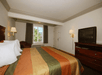 A king bed and a small TV, two lamps, a chair and a window in a non-smoking room at Cloverdale Wine Country Inn & Suites.