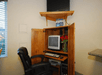 A small business center  with an office chair, desk, computer, and television at Cloverdale Wine Country Inn & Suites.
