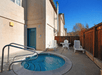 Outdoor spa tub with chair and a small table on the side near a tall fence on a sunny day at Cloverdale Wine Country Inn & Suites.
