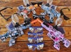 Three paintball guns with colorful patterns, safety goggles, and accessories arranged on a wooden surface.