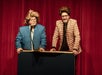 Stretch Mccord & Lex Pearson on a platform with buzzer as they tell jokes.