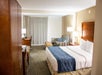 A comfortable guest room with a king bed, seating area with a sofa bed, flat-screen TV, and a work desk, designed for relaxation and productivity.