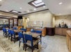 A dining area with blue chairs and wooden tables. A buffet station is at the back, surrounded by wooden cabinetry. The room has skylights and decorative wall patterns.