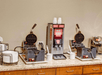 A waffle making station with two waffle makers and a batter dispenser in between them at the breakfast buffet at the Comfort Inn Conference Center Pittsburgh.
