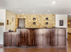 A dark brown worn wooden front desk with a yellow and white stone wall behind it at the Comfort Inn Denver Central.
