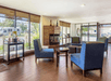 A lounge area in the lobby of the Comfort Inn Denver Central with several floor to ceiling windows, blue chairs, small brown side tables, and a small fireplace.