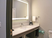 Modern bathroom with a sleek sink, illuminated mirror, towel rack, and toiletries.