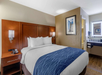 One king bed, lamps and a telephone inside a guest room.