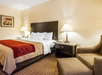 One king bed, bedside lamps and a comfortable armchair inside a guest room.