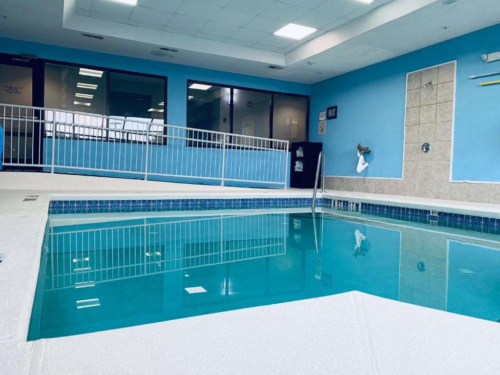 Indoor swimming pool with a ramp leading into it, surrounded by blue walls and large windows.