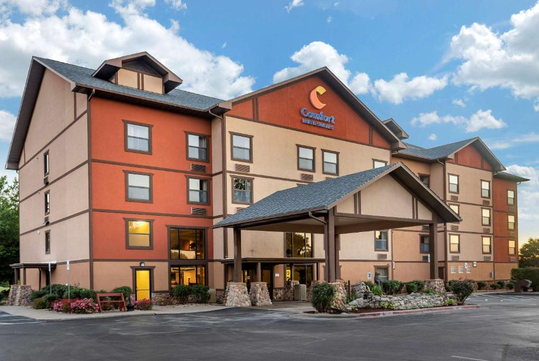 A four-story hotel building with a sign that reads "Comfort Inn & Suites" and a covered entrance.
