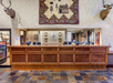 Hotel front desk area with wood counter, hunting trophies mounted on the walls, and a decorative quilt featuring animals and a cabin motif.