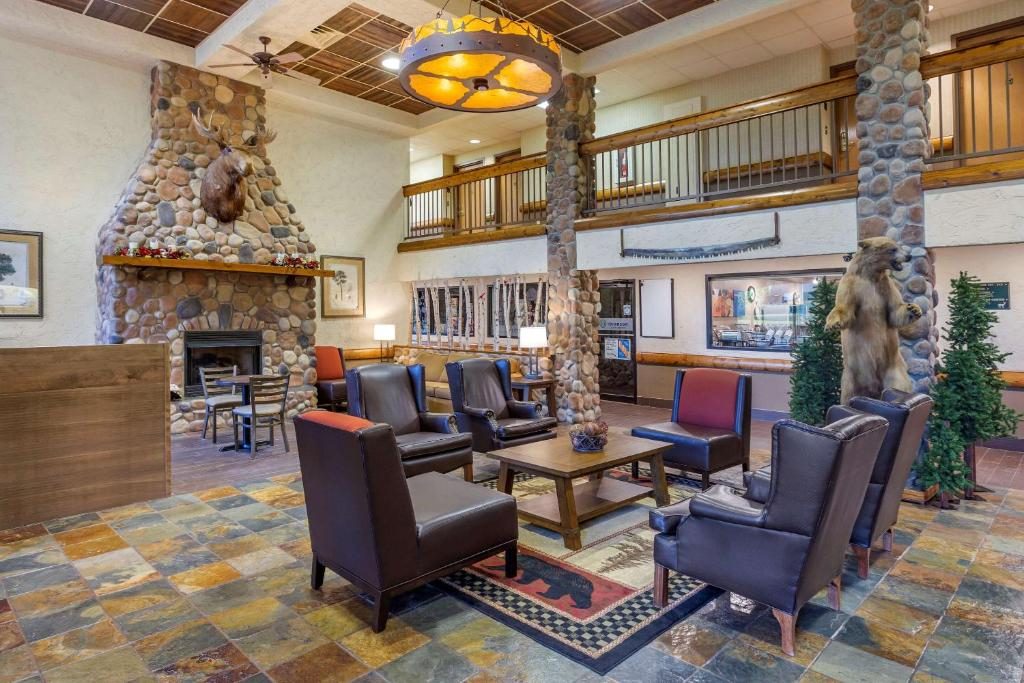 Hotel lobby with stone fireplace, leather chairs, rustic decor, and animal mounts on the walls. A large chandelier hangs from the ceiling, creating a cozy atmosphere.