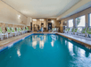 Indoor pool surrounded by sun loungers and big windows.