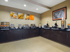 Breakfast area with a variety of breakfast items, assorted fruits, juice machine and more.